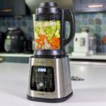 Blender chauffant Moulinex Perfectmix Cook avec légumes crus dans le bol en verre pendant un programme soupe