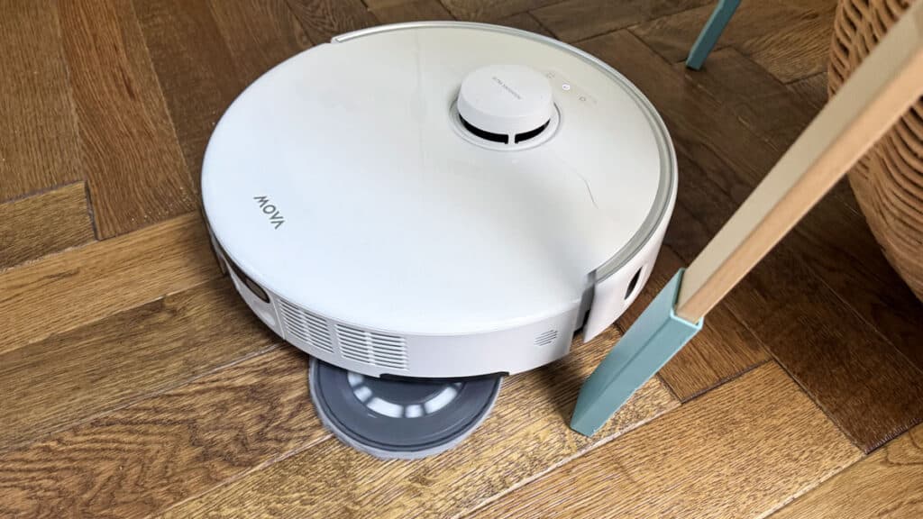 Aspirateur robot Mova P70 Pro Ultra déployant sa brosse latérale extensible pour atteindre la poussière sous un meuble