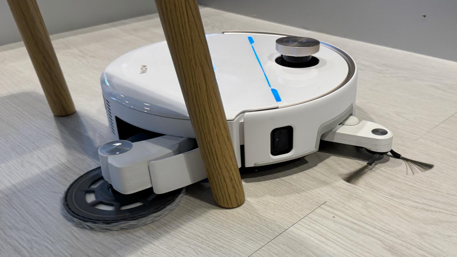 Serpillière déportée du Mova V70 Ultra Complete en train de nettoyer autour d’un pied de chaise