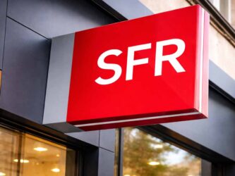 Enseigne rouge avec le logo SFR sur la façade d'une boutique, symbolisant le rachat de l'opérateur par Orange, Free et Bouygues Telecom