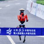 Un robot humanoïde rouge et noir en chine franchit en courant le ruban de la ligne d'arrivée et pulvérise le record du semi-marathon de Pékin