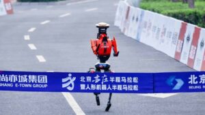 Un robot humanoïde rouge et noir en chine franchit en courant le ruban de la ligne d'arrivée et pulvérise le record du semi-marathon de Pékin