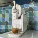 Verre de granité au Coca-Cola posé devant la machine Moulinex Freezi vue de trois quarts.