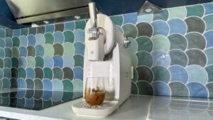 Verre de granité au Coca-Cola posé devant la machine Moulinex Freezi vue de trois quarts.