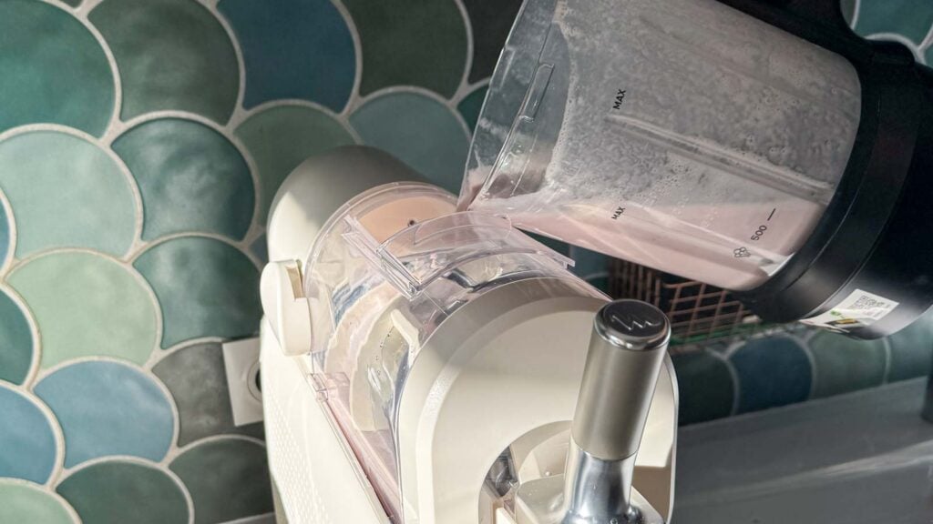 Préparation de glace à la fraise versée depuis le bol du blender dans la machine Moulinex Freezi