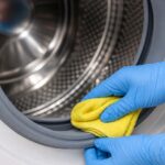 Personne nettoyant le joint d’une machine à laver à hublot avec un chiffon microfibre jaune