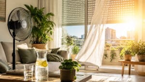 Salon lumineux avec ventilateur, plantes et volet entrouvert pour garder la maison fraîche en été