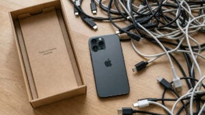 Boîte de smartphone vide entourée de plusieurs câbles USB-C différents, illustration de la confusion autour des normes de charge et de transfert.