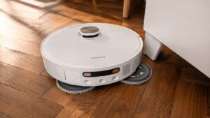 Le robot aspirateur laveur Dreame L40 Ultra AE nettoie un parquet au plus près d’un meuble