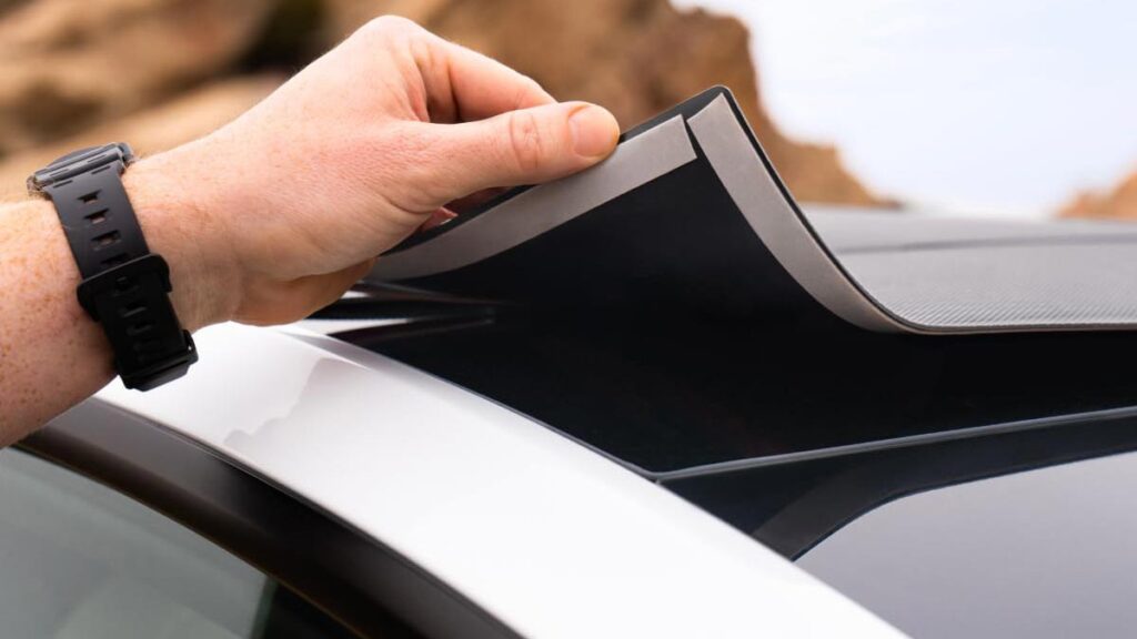 Pose du film solaire amovible EcoFlow HeatGuard sur le toit vitré d'une Tesla à l'aide d'un adhésif.