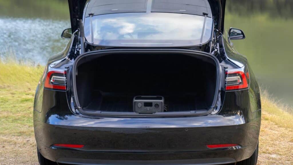 Station d'alimentation portable EcoFlow dans le coffre ouvert d'une Tesla reliée au panneau solaire HeatGuard.
