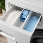 Tiroir à lessive d’un lave-linge ouvert avec ses trois compartiments pour le prélavage, la lessive principale et l’adoucissant.