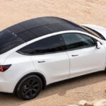 Tesla Model Y blanche équipée d’un panneau solaire sur son toit panoramique.