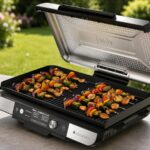 Plancha Ninja Sizzle Pro XL en train de cuire des brochettes sur une table au jardin