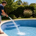 Un homme remplit une piscine privée avec un tuyau d’arrosage en période de fortes chaleurs