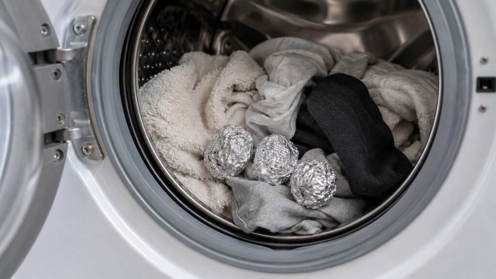 Boules de papier aluminium placées dans le tambour d’un lave-linge avec du linge