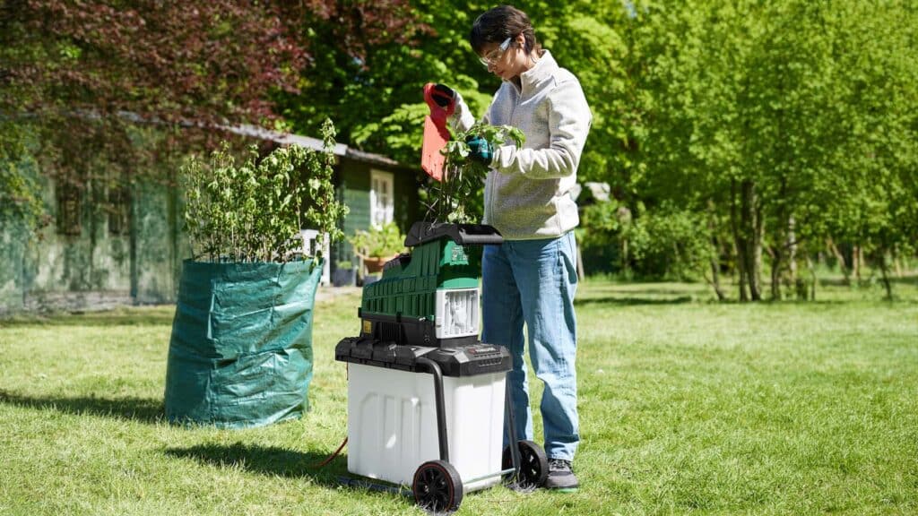 Personne utilisant le broyeur de végétaux Parkside dans un jardin