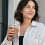 Femme tenant un café dans un gobelet en plastique