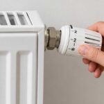 Main réglant le robinet thermostatique d’un radiateur avant l’hiver.