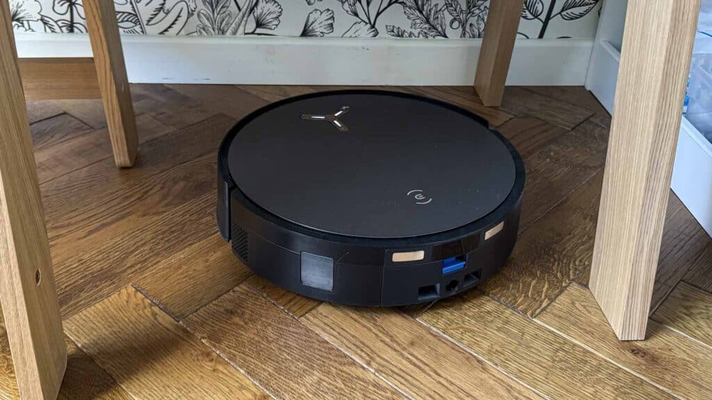 Aspirateur robot laveur à rouleau Ecovacs Deebot X11 pendant notre test, entre un pied de table et une chaise