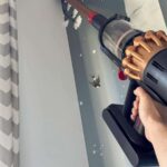 Aspirateur balai Dyson V16 Piston Animal utilisé en hauteur pour aspirer le haut d’un mur