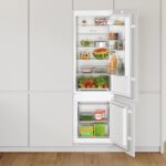Réfrigérateur combiné encastrable Bosch de la gamme du KIV87NSE0, intégré dans une cuisine, portes ouvertes