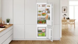 Réfrigérateur combiné encastrable Bosch de la gamme du KIV87NSE0, intégré dans une cuisine, portes ouvertes