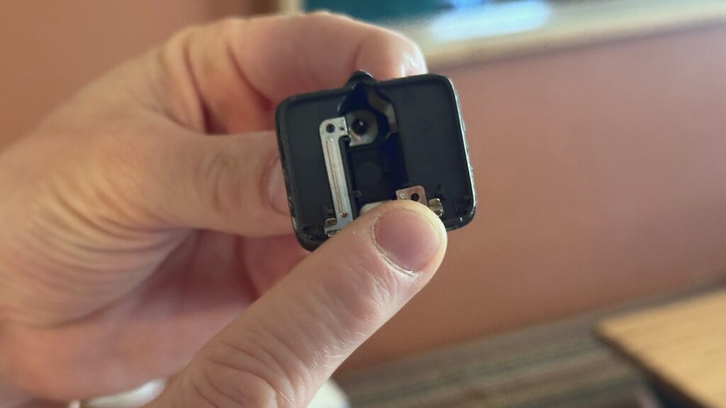 Doigt montrant les deux lamelles de métal à nu dans la partie fiche d’un chargeur USB-C cassé