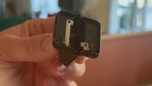 Main tenant la partie d’un chargeur USB-C cassé restée dans la prise : les broches dépassent dessous et deux lamelles de métal sont à nu sur le dessus