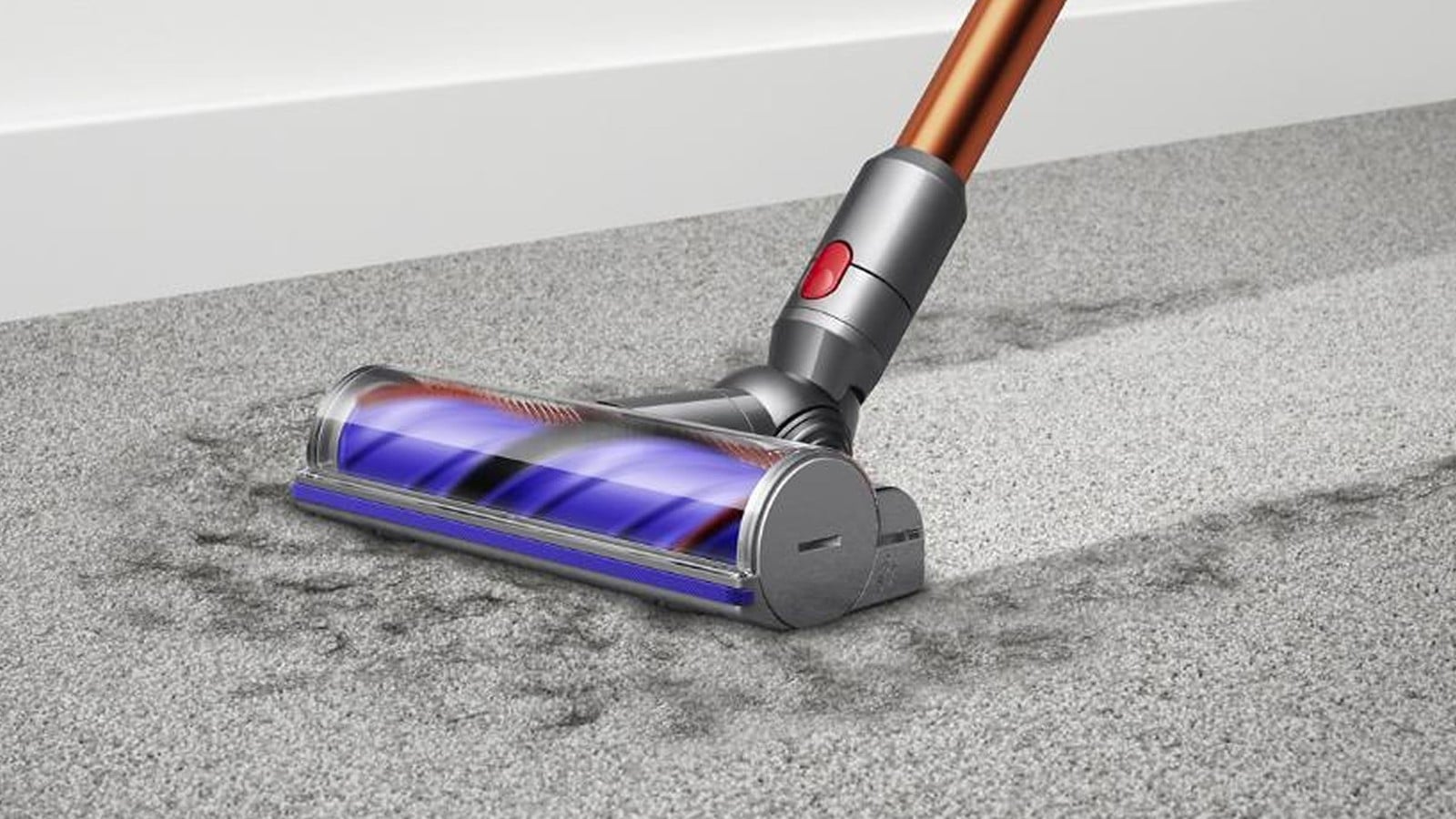 Brosse Motorbar du Dyson Cyclone V10 sur une moquette grise le long d’une plinthe