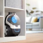 Aspirateur traîneau Philips PowerPro Compact blanc rangé dans un meuble ouvert d’un salon